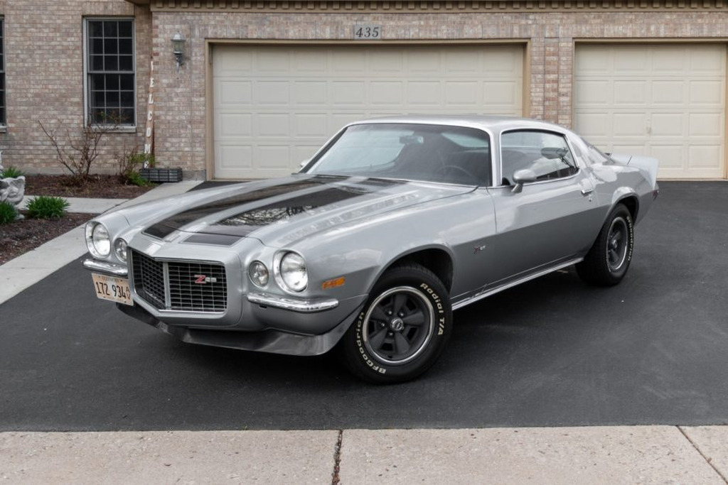 AI caption: a silver muscle car parked in front of a garage, car