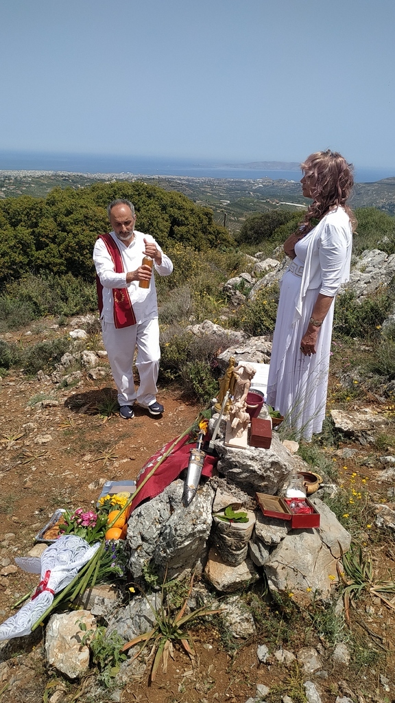 AI caption: a group of people standing on a hill with flowers, portrait a woman is laying flowers on a hillside, the woman is laying flowers on a grave, portrait two people standing on a hill with flowers and a statue, the woman is dressed in white and the man is dressed in black