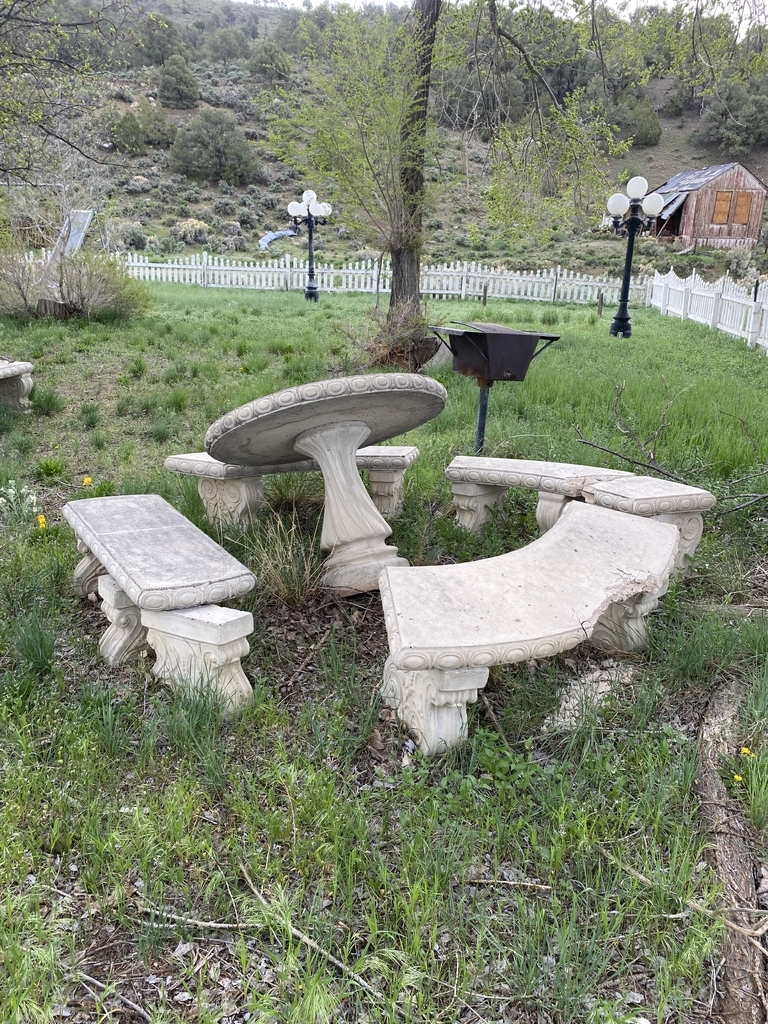 AI caption: a small building with a sign that says own of lone inc, old fashioned spirits of vitlettes gas sign, the sign is a slang term for a gas station, vintage a stone bench in a grassy area, the stone benches are too close to the grass