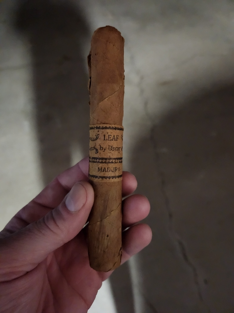 AI caption: a person holding a cigar with a label on it, hand holding a cigar